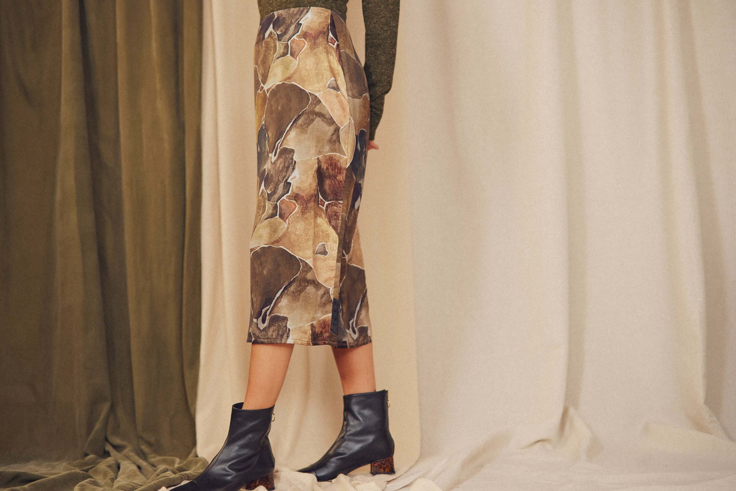 Side view of a person wearing a Printed Ecovero Pencil Midi Skirt with a multicoloured print and stylish boots.
