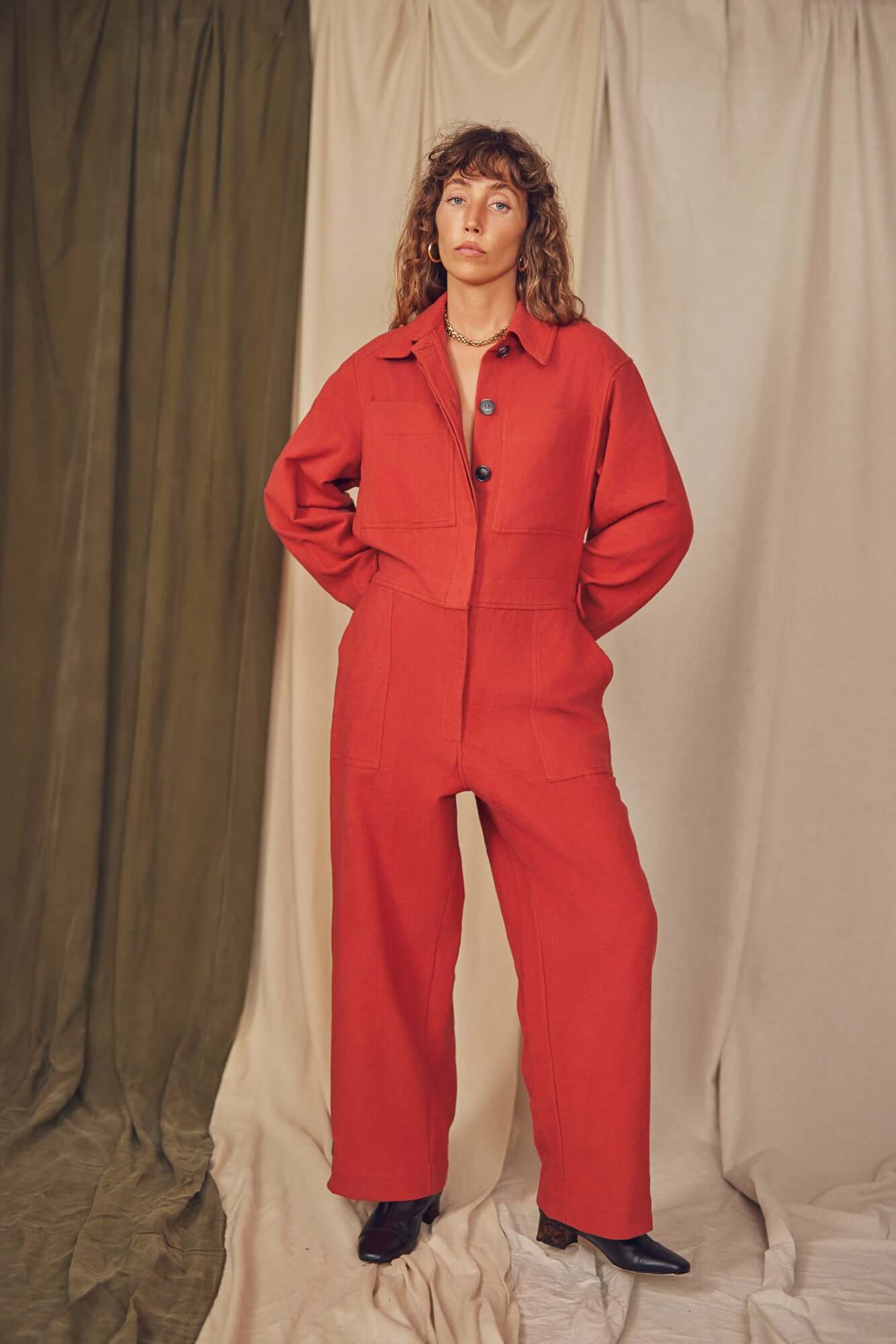 Model wearing a Rust Organic Cotton Boiler Suit against a neutral backdrop, showcasing eco-friendly fashion.