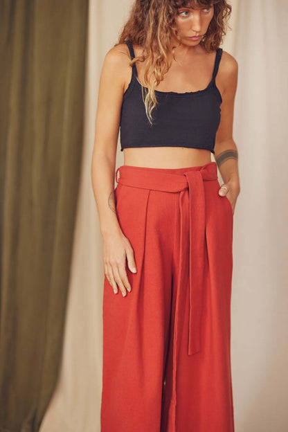 Model wearing Rust Organic Cotton Wide Trousers with detachable belt and black crop top.