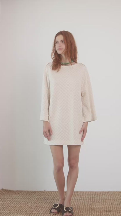 Model wearing an Organic Cotton Crochet Mini Dress with flared sleeves in ecru color.