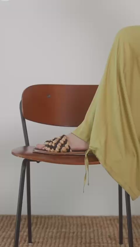 Wide Ecovero Trousers in Soft Olive displayed on a seated model, showcasing relaxed styles with elegant footwear.