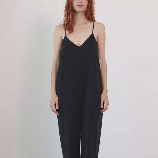 Model wearing Organic Cotton Wide Jumpsuit in Black, featuring a relaxed silhouette and slim straps.