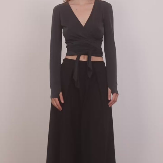 Model wearing Cupro Multiway Wrap Top in Slate Black paired with a black skirt.