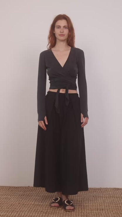 Model wearing Cupro Multiway Wrap Top in Slate Black paired with a black skirt.