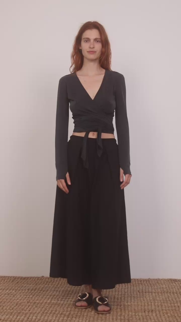 Model wearing Cupro Multiway Wrap Top in Slate Black paired with a black skirt.