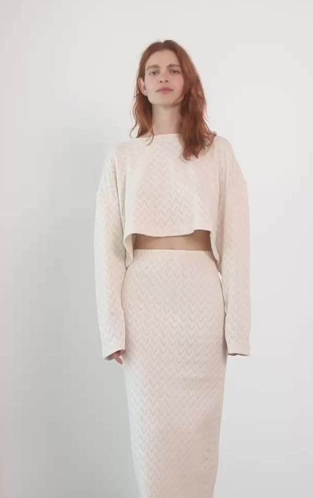 Model showcasing a Crochet Organic Cotton Midi Skirt and matching top in ecru, highlighting texture and modern style.