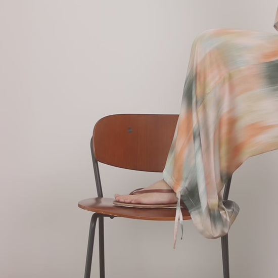 Printed Ecovero Viscose Wide-Leg Trousers draped stylishly over a chair, showcasing their fluid silhouette and colorful print.