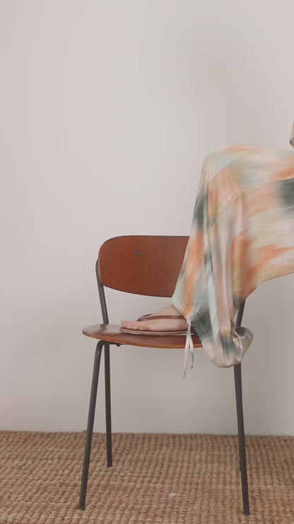 Printed Ecovero Viscose Wide-Leg Trousers draped stylishly over a chair, showcasing their fluid silhouette and colorful print.