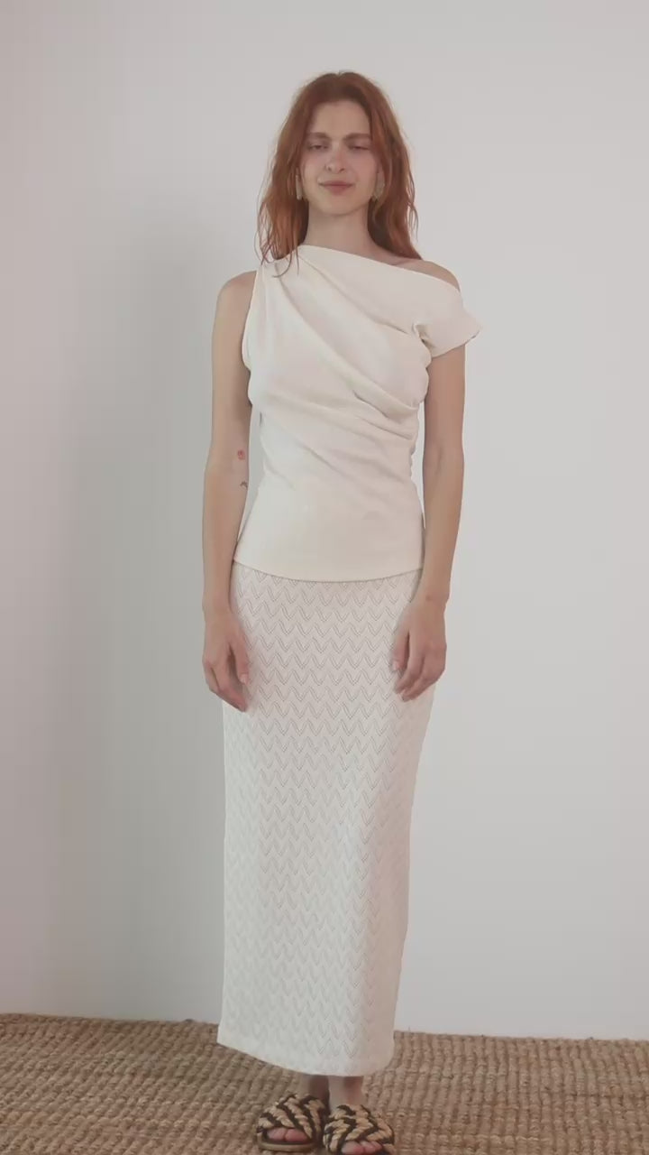 Model wearing a Banana Pineapple Drape Neckline Top in Ecru paired with a textured white skirt.